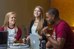 3 Kelley students sit at a table working on their studies.